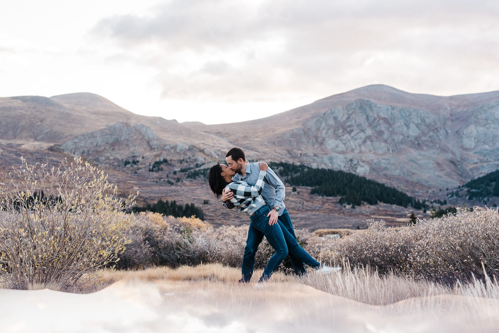 Couple dips on the top of Guanella Pass in Colorado. Guanella Pass is one of the best engagement photo locations in Colorado and near Denver. The rocky mountains on top of the pass are dramatic and shaded in colors of purple and pink.