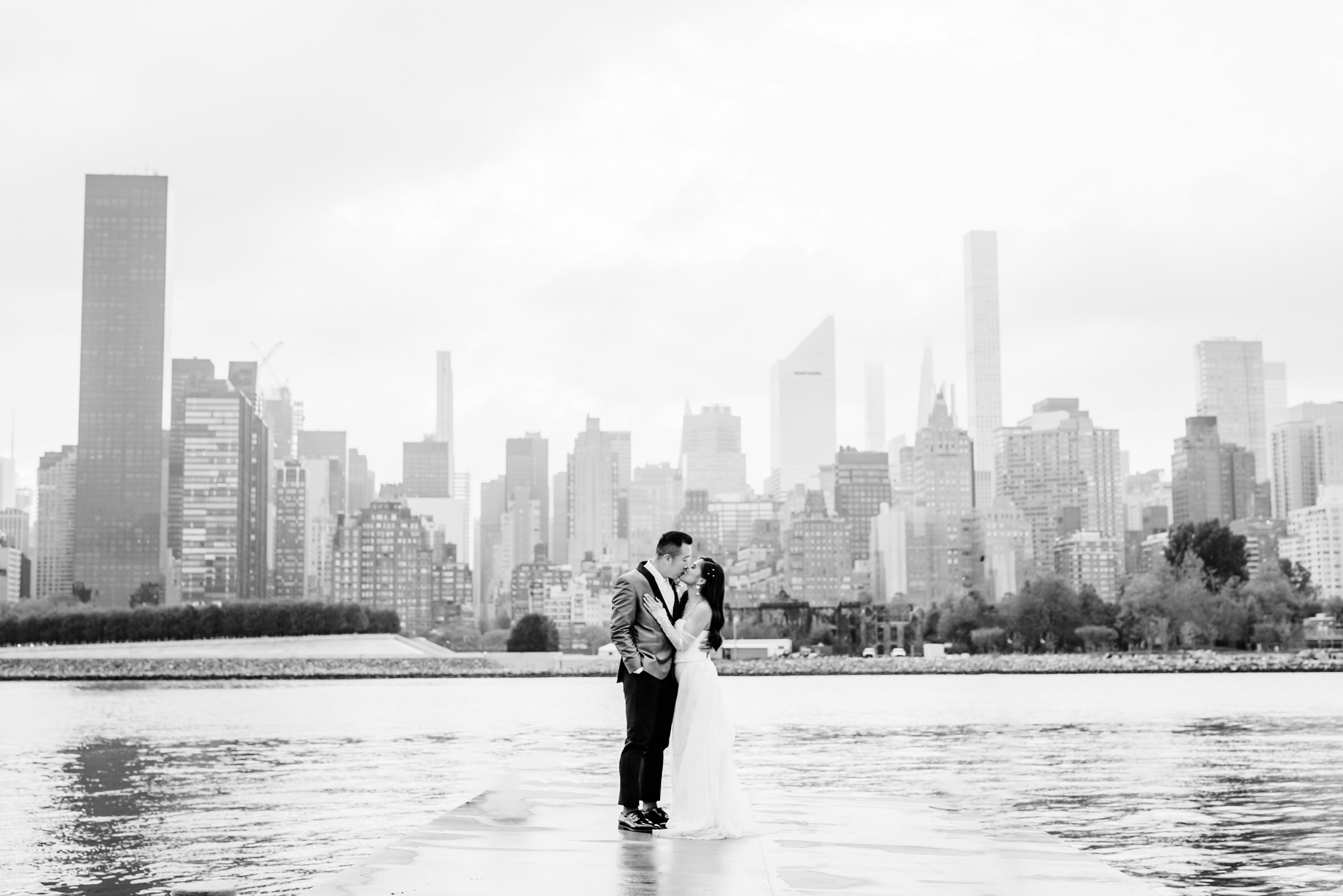 Destination wedding photographer captures bride and groom kissing in front of the New York City skyline in the background